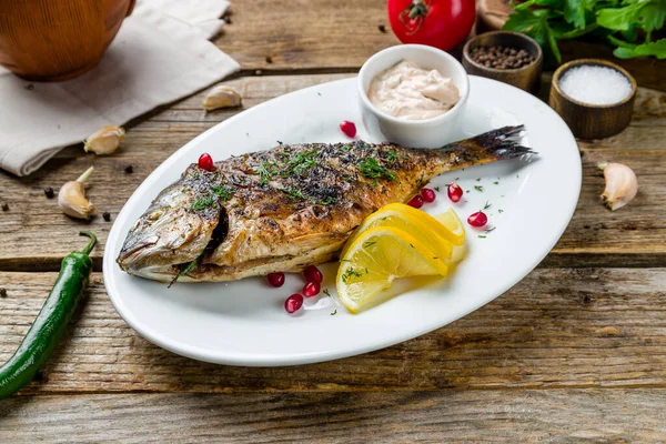 Dorado ızgarada beyaz tabakta eski ahşap masada