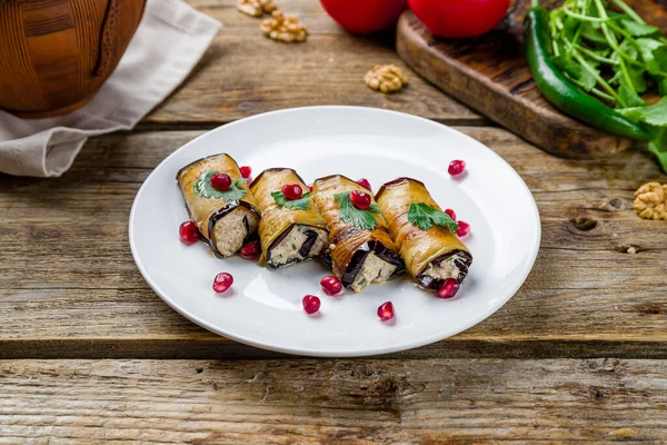 Eggplant rolls stuffed with nuts on old wooden table