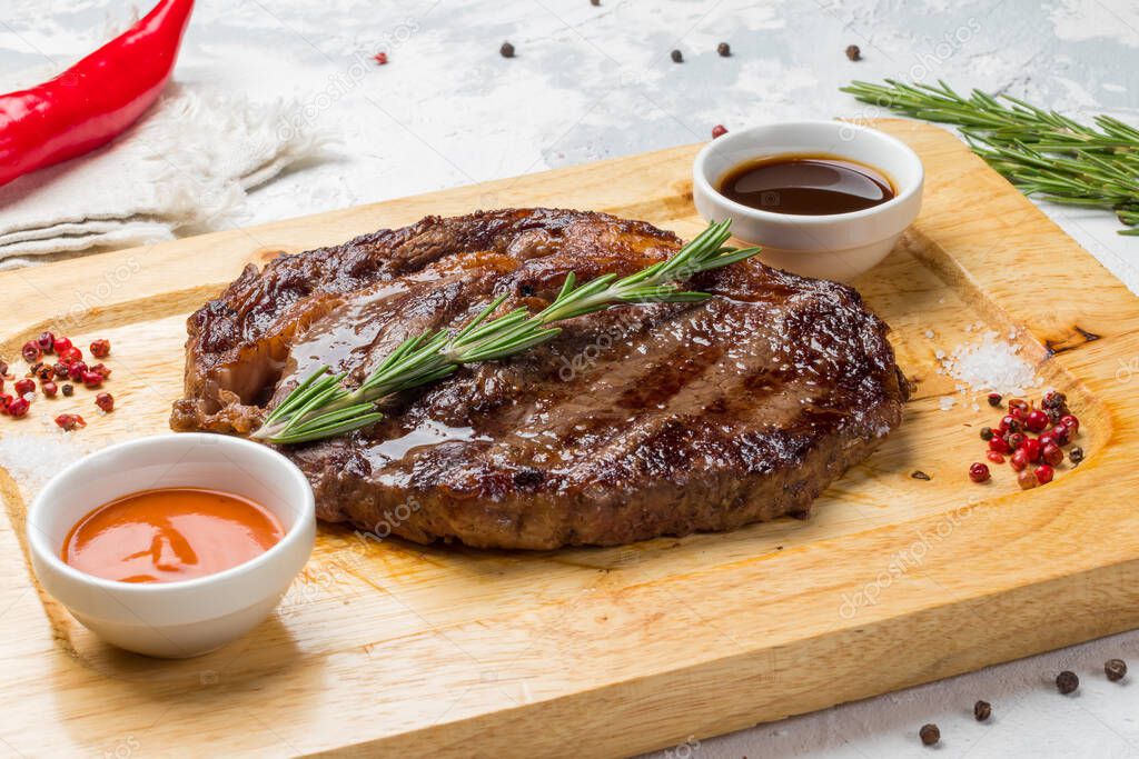 juicy Ribeye steak, beefsteak with sauces and rosemary on wooden board