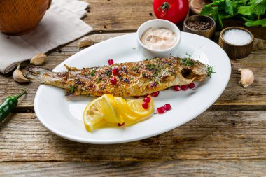 Eski ahşap masada ızgara alabalık.