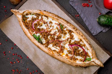 Kıyma ve peynirli Türk pidesi ve dilimlenmiş kırmızı soğan.