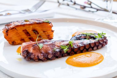 Beyaz ahtapot ızgara tabakta beyaz ahşap masada.