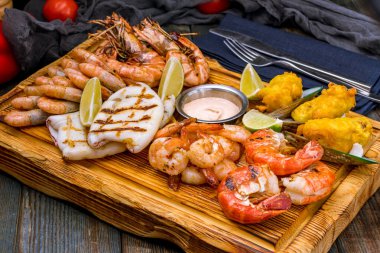 Mavi ahşap masada ızgara yapılmış çeşitli deniz ürünleri.