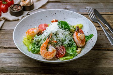 Eski ahşap masadaki karidesli salata sezarı.
