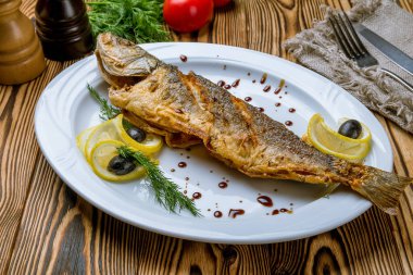 Beyaz tabakta kızarmış levrek. 