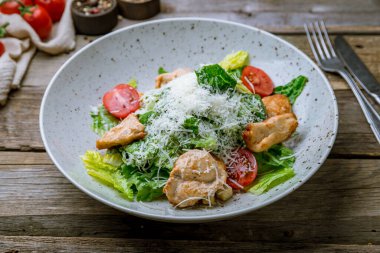 Eski ahşap masada tavuklu salata sezarı.
