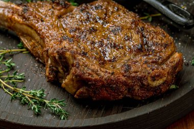 Tahta arka planda lezzetli Tomahawk bifteğinin yakın plan görüntüsü.