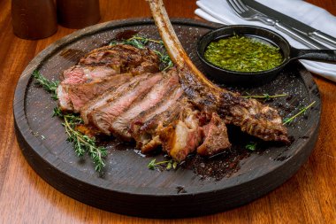 Tahta arka planda lezzetli Tomahawk bifteğinin yakın plan görüntüsü.