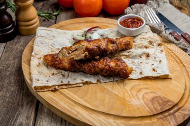 Ahşap arka planda soslu kuzu kebabı.