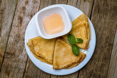 Ballı krepler ve ahşap arka planda nane yaprakları.