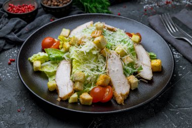 Siyah tabakta tavuklu salata sezarı.