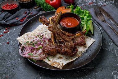 Siyah tabakta kuzu eti ve domates sosu.