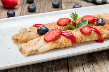 Böğürtlenli krep ve ahşap zemin üzerinde nane.