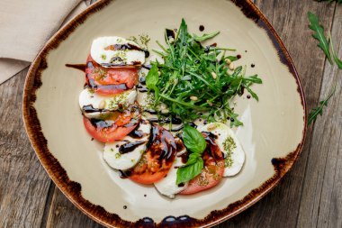 Mozzarella soslu Caprese salatası ve eski ahşap masada domates.