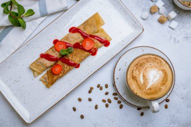 Böğürtlenli krep ve gri arka planda kahve kapuçino.