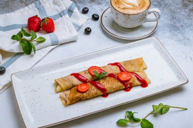 Böğürtlenli krep ve gri arka planda kahve kapuçino.