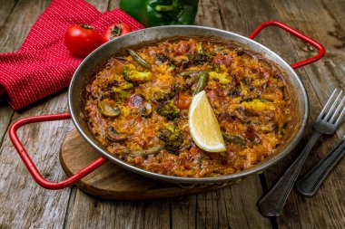 Ahşap arka planda sebzeli İspanyol paella.