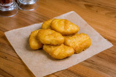 Kızarmış tavuk külçeleri ahşap masada.