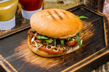 Domatesli lezzetli hamburger, ahşap tahtada roka ve peynir.