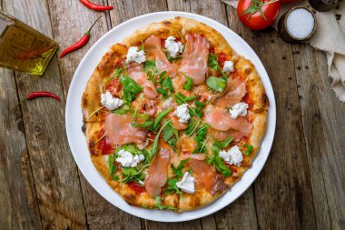 Somonlu pizza, Philadelphia peyniri ve ahşap masada aragula.