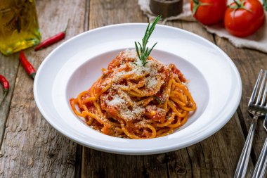 Tahta masadaki beyaz tabakta makarna bolonez.