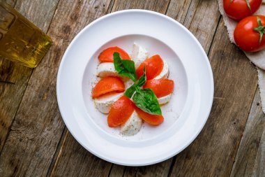 Mozzarella, domates ve basil ile ahşap masada Caprese salatası