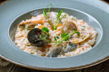 Lezzetli risotto, deniz ürünleri ve ahşap masada pilav.