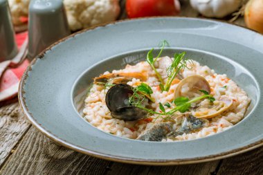 Lezzetli risotto, deniz ürünleri ve ahşap masada pilav.