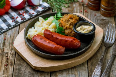 fried pork sausages with mashed potatoes, fried cabbage and sause on wooden background