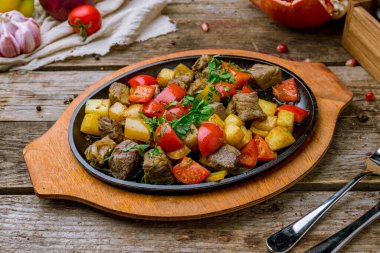 Kızarmış kuzu ve sebzeler, dökme demir tavada.