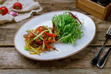 Eski ahşap masada biftek ve sebzeli biftek salatası.