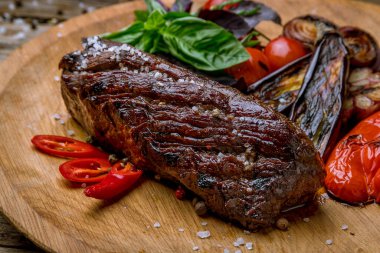 Eski ahşap masada ızgara sebzeli şato bifteği. Yakın plan.