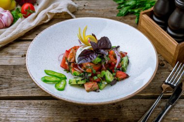 Domatesli sebze salatası, salatalık, kırmızı soğan ve eski ahşap masa üzerine basil.