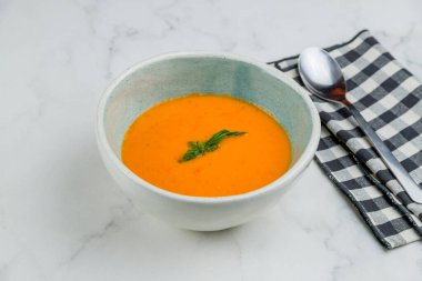 Beyaz mermer masada basil soslu domates çorbası.