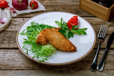 Eski ahşap masada karışık salatalı tavuk pirzolası.