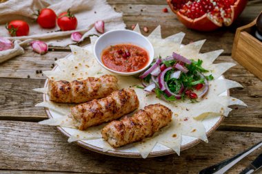 Eski ahşap masada soğanlı ve domates soslu Lula kebabı tavuk.
