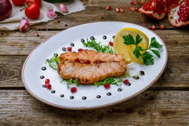 Limonlu mersin balığı bifteği ve eski ahşap masada kestane rengi tabak.