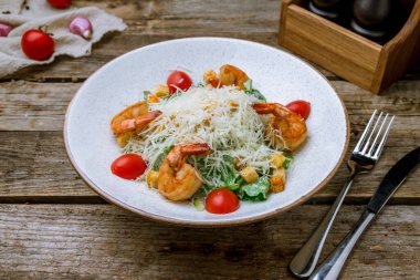 Salata sezarı, beyaz tabakta karides ve eski ahşap masa.