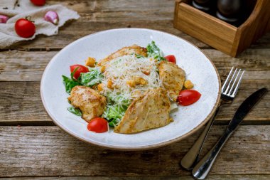 Eski ahşap masada tavuklu salata sezarı.