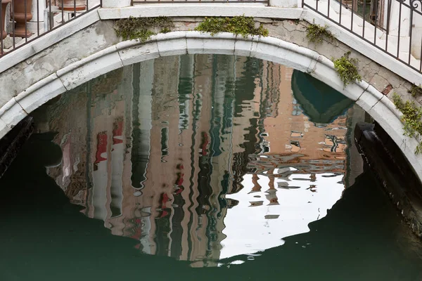 Reflejos de casas venecianas bajo un puente peatonal típico, Venecia, Italia —  Fotos de Stock