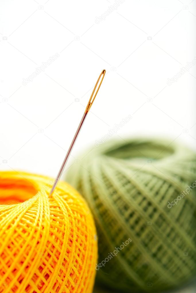 Close-up needle in color clews on white background