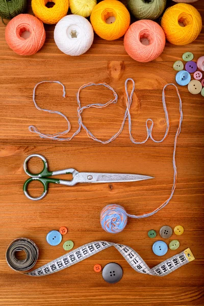 Word "sew" with sewing tools and accesories on wooden background — Stock Photo, Image