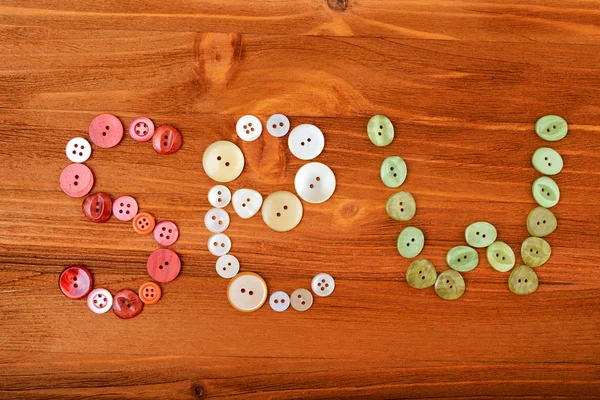 Mot "coudre" à partir de boutons de couture multicolores sur fond en bois — Photo