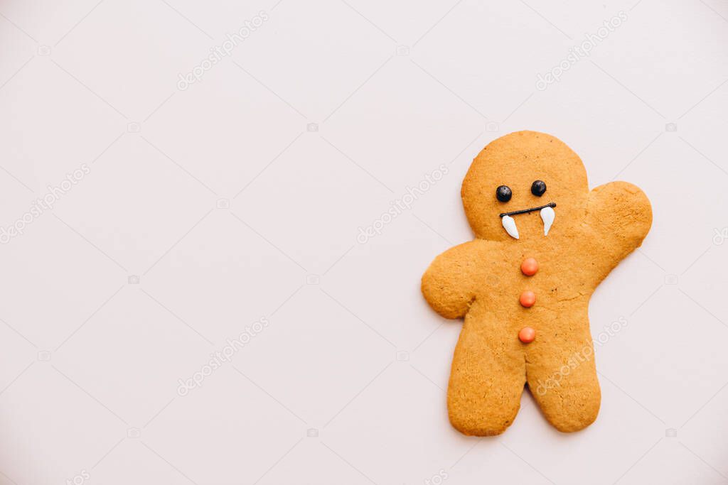 cookies in the shape of ginger men with a vampire face prepared for Halloween lie on a pink background. Halloween background