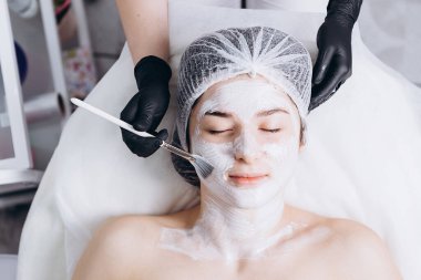 01.02.2020 Kyiv, Ukrayna: Yüze spa tedavisi yapmak için kozmetik uzmanına gelen genç bir bayan müşterinin portresi (masaj, soyma ve maske). Güzellik ve kendine bakım kavramı