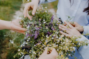 Uzun gömlekli çekici bir kadın otların ve kır çiçeklerinin arasında fotoğraf çektirmek için poz veriyor.