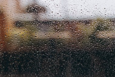 Panoramik pencereye yağmur damlaları, sağanak yağış sırasında şehir caddesinde bir kahve dükkanının ortasından manzara. seçici odak, kopyalama alanı