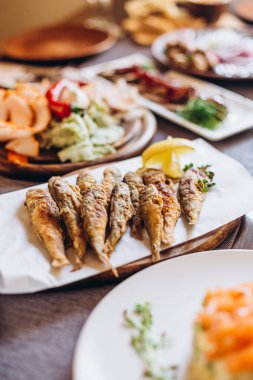 Slav usulü çeşitli lezzetli yemeklerle kaplı ev ahşap masa: ekşi ekmek hamuru, tuzlu ve kızarmış balık, patates, kızarmış et ve salata