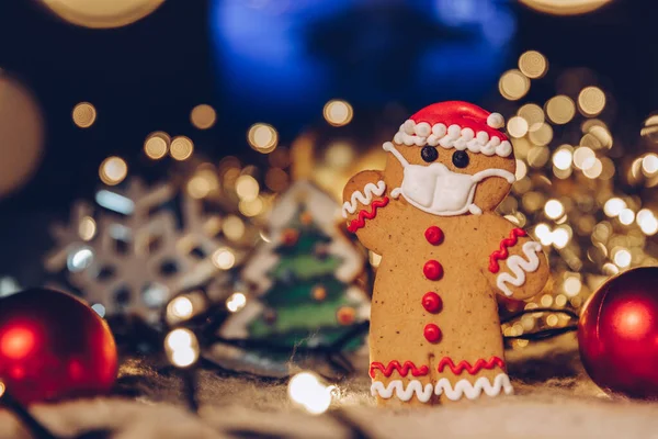 Yüzlerine tıbbi koruyucu maske takan zencefilli çöreklerle dolu bir Noel arkaplanı. Bir koronavirüs salgını sırasında 2021 yılını evde kutlama konsepti. Boşluğu kopyala