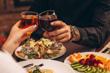 Gözlüklü eller Noel ağacı ışıklarının arka planına vuruyor ve nefis yemeklerle dolu bir masada şöminenin üzerinde şenlik ateşi yanıyor.